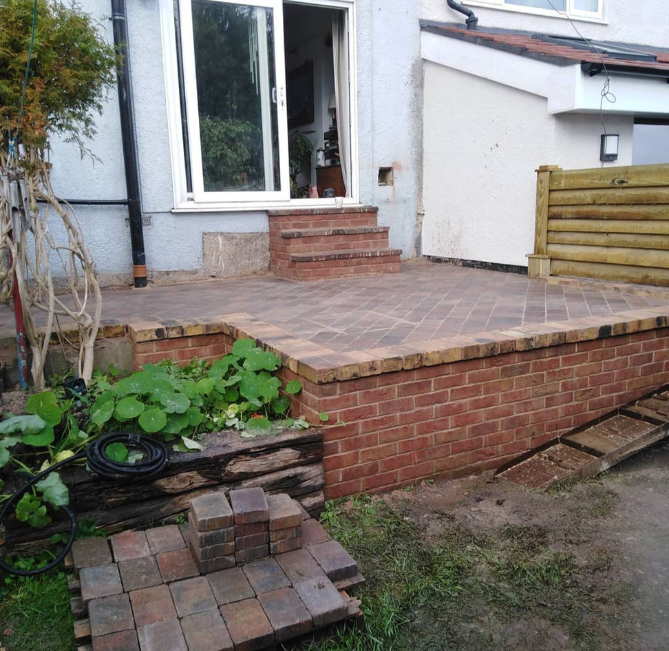 a patio with a retaining wall and bricks